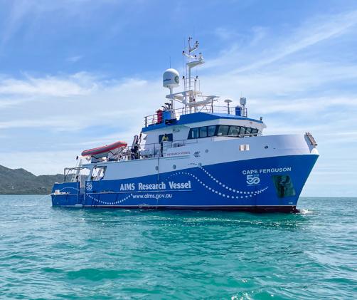 blue and white research vessel on water with island in background